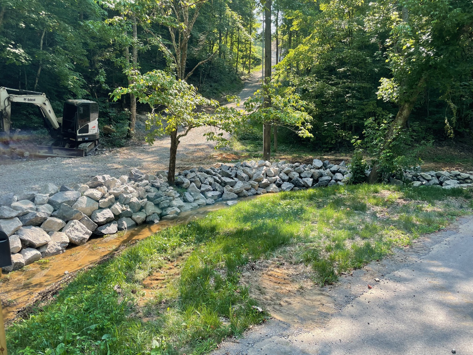 Stone retaining wall built along a driveway and small stream