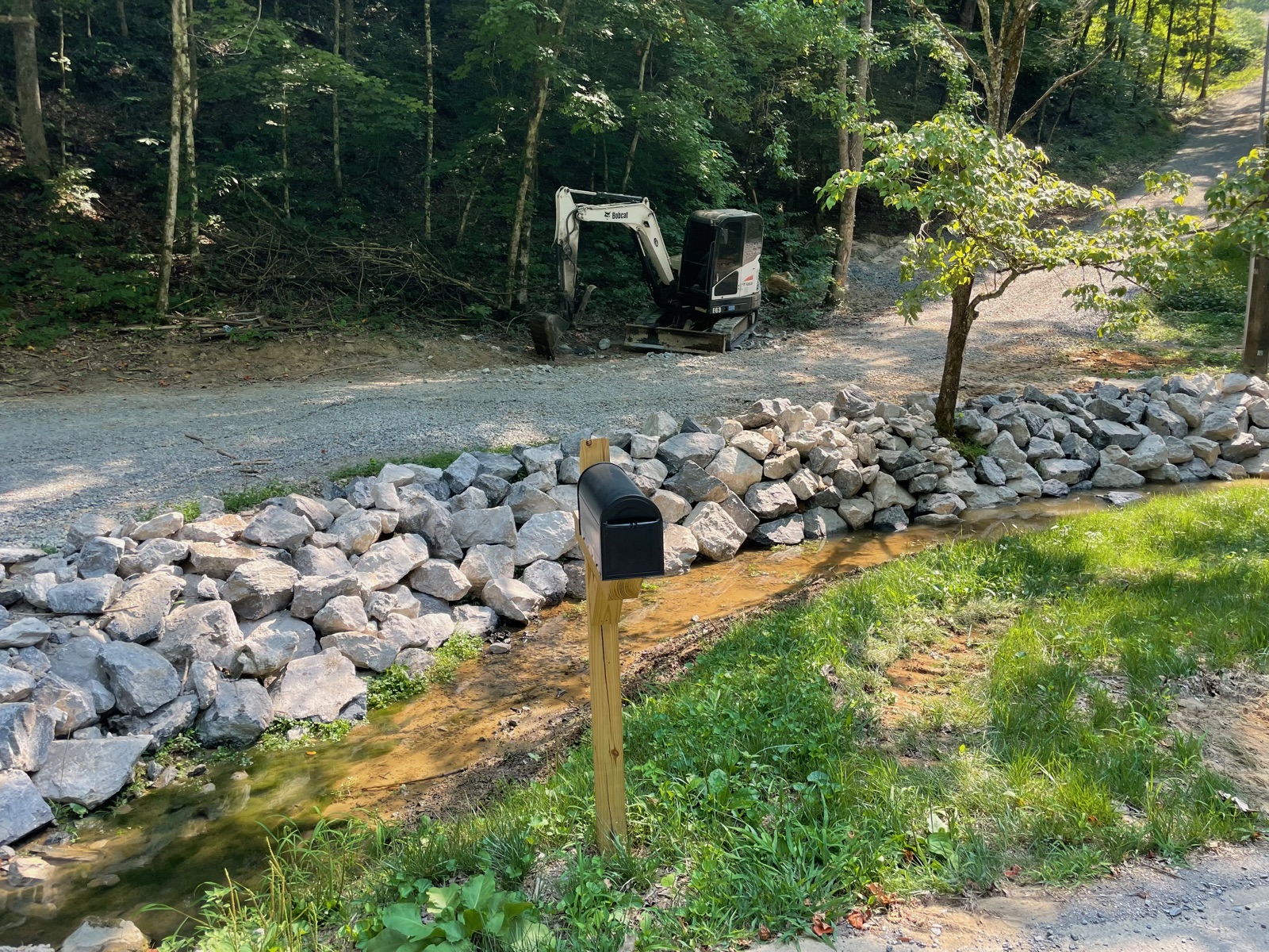 Stone retaining wall and culvert with new mailbox at driveway entrance