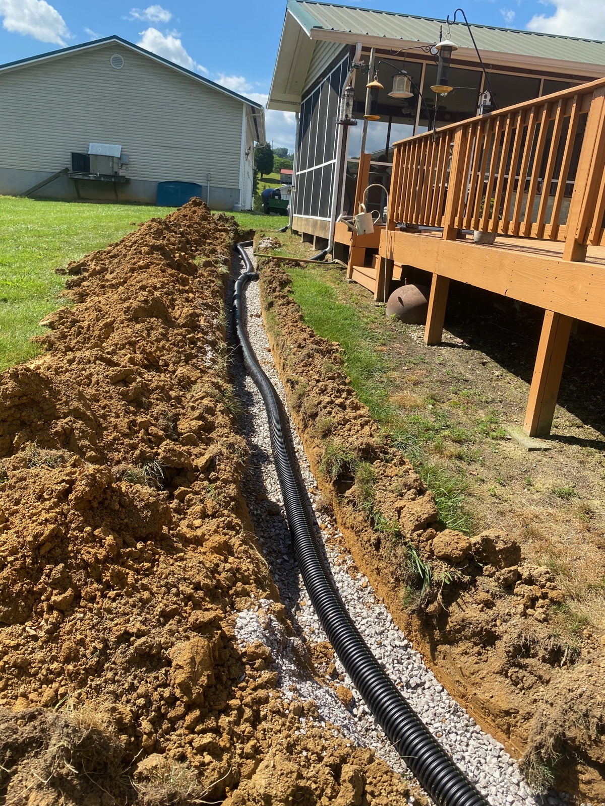 Drainage line trenched and run alongside a residential deck