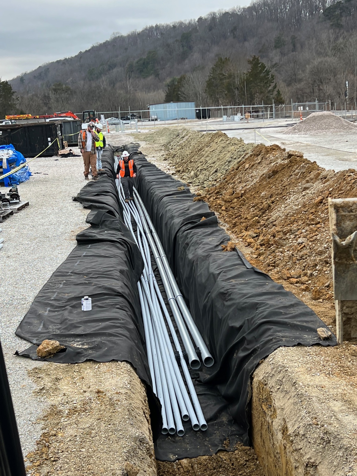 Workers laying PVC pipe in a long lined utility trench