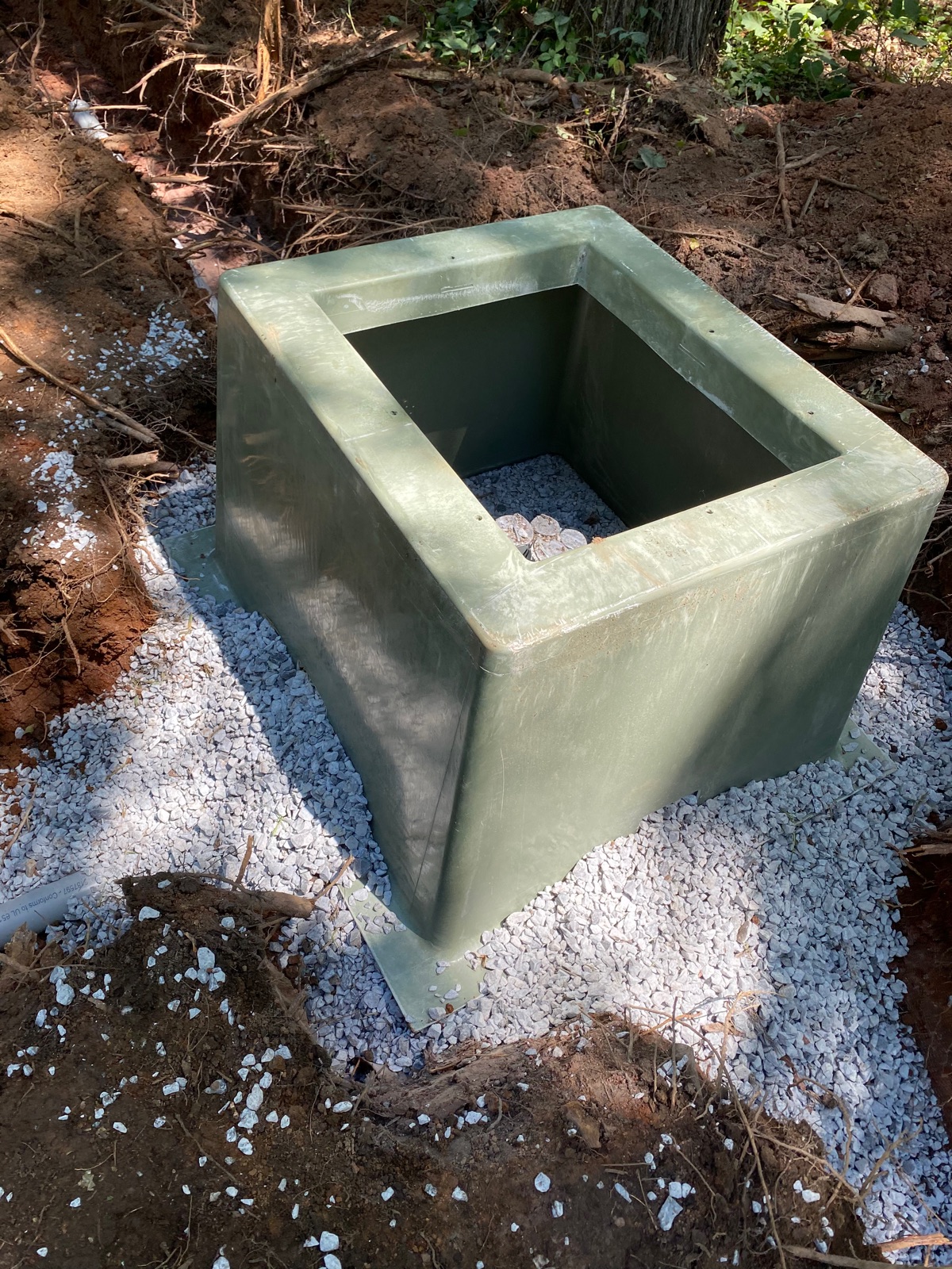 New green fiberglass septic distribution riser set on gravel