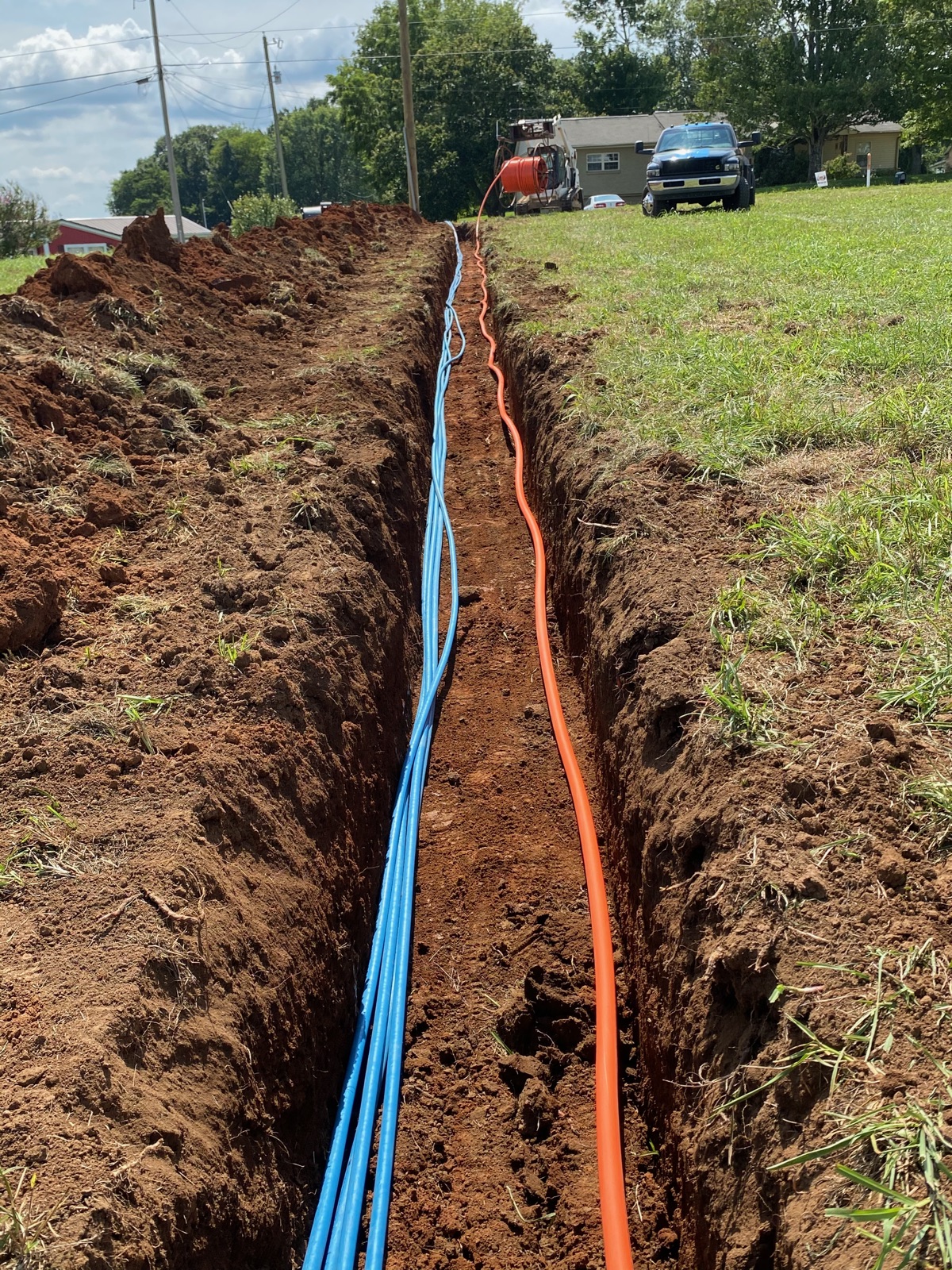 Utility trench with blue water and orange electrical conduit run