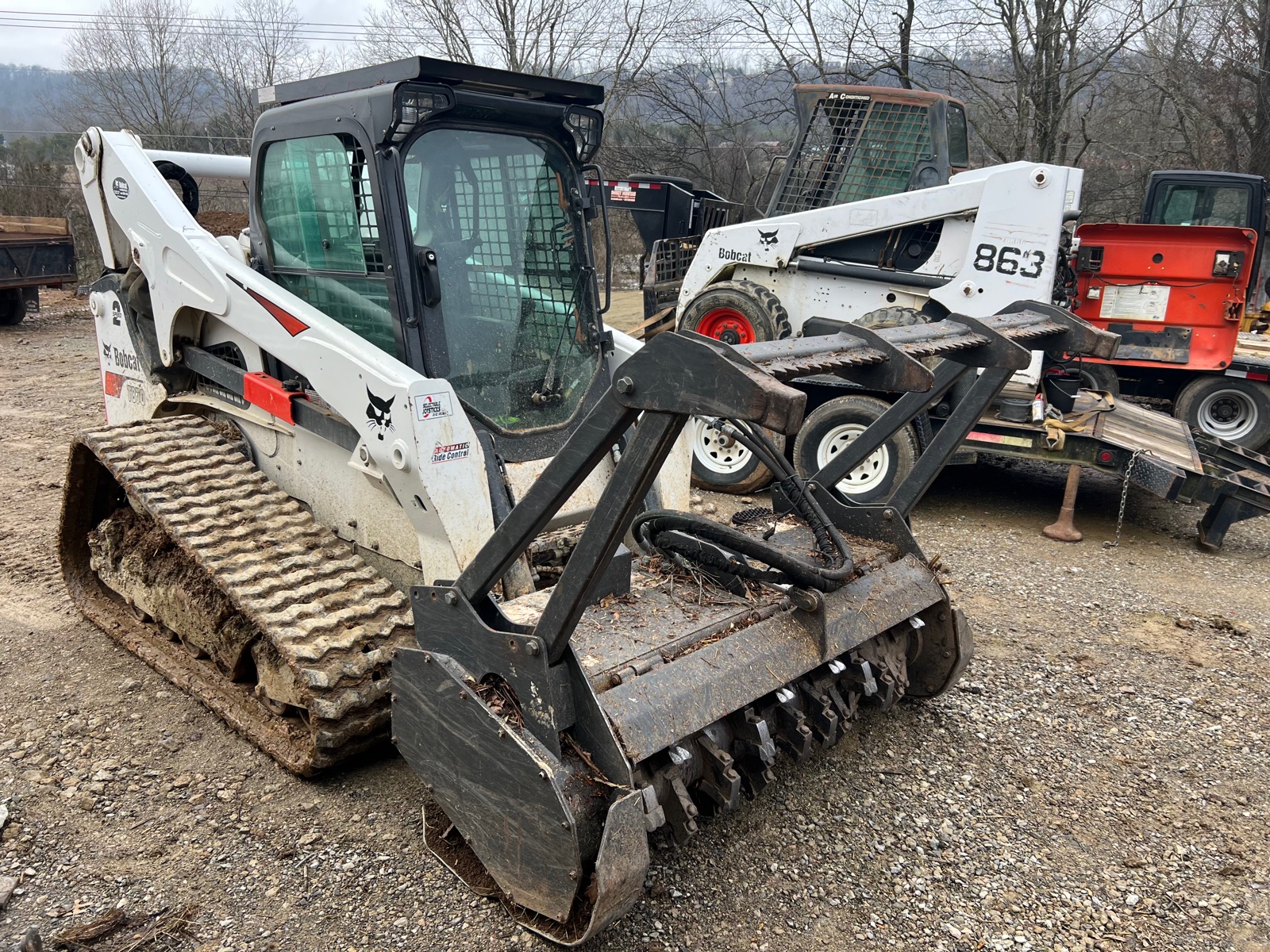 Bobcat skid steer with forestry mulcher attachment in equipment yard