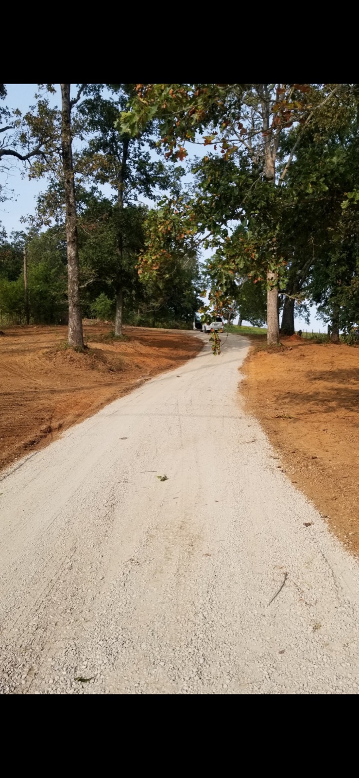 Finished gravel driveway curving up a wooded hillside