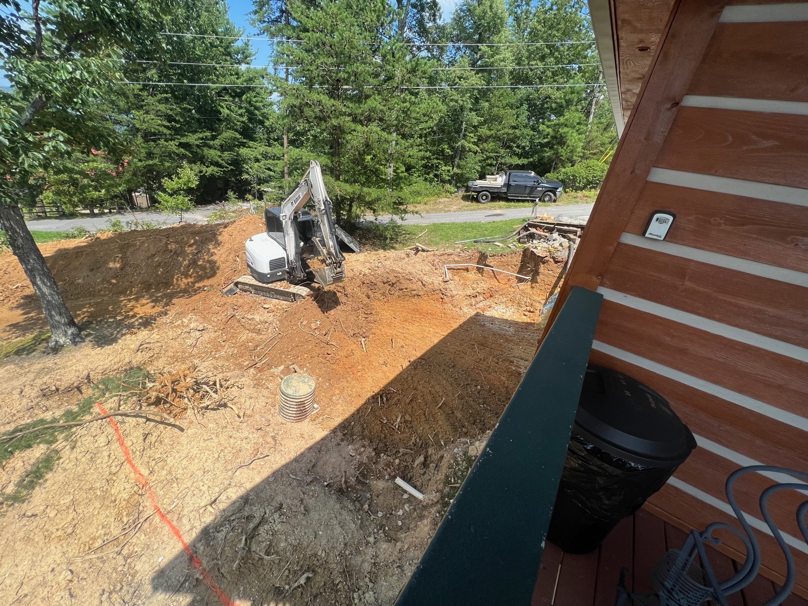 Skid steer doing site work behind a wooded cabin
