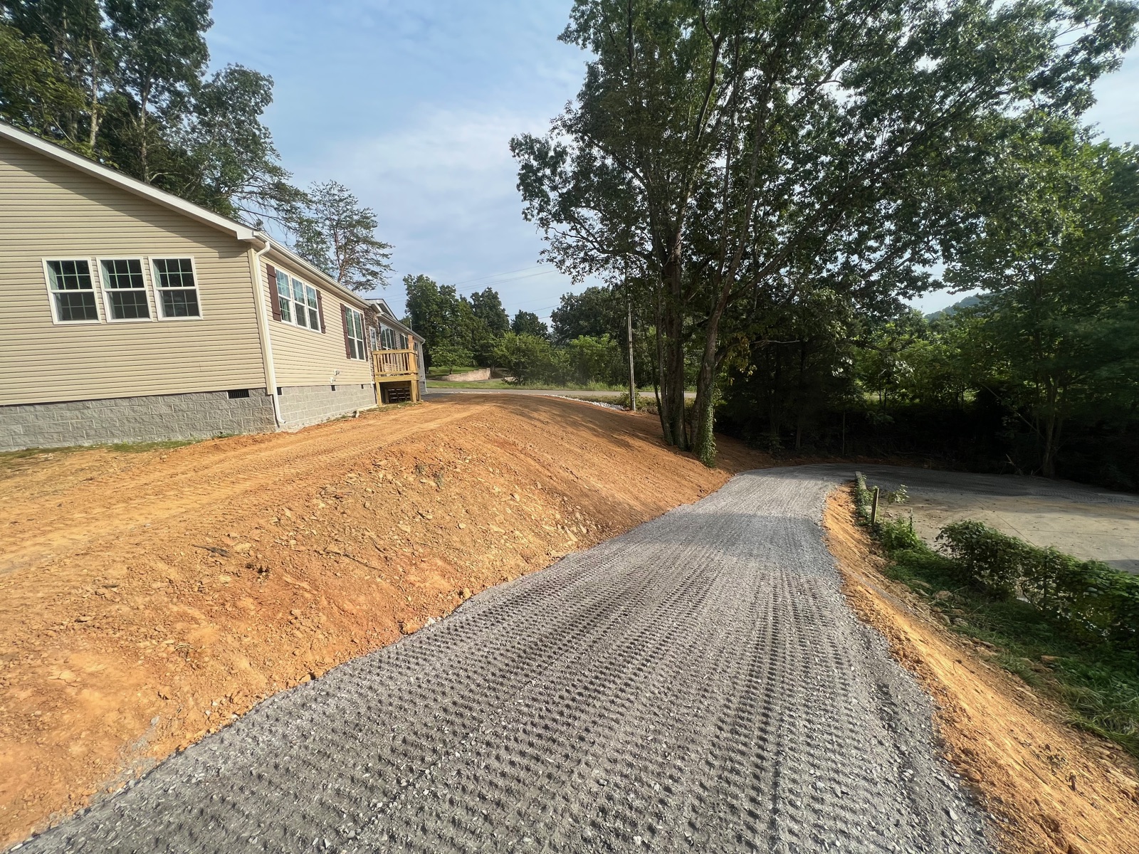 Finished gravel driveway leading to a new home with retaining slope