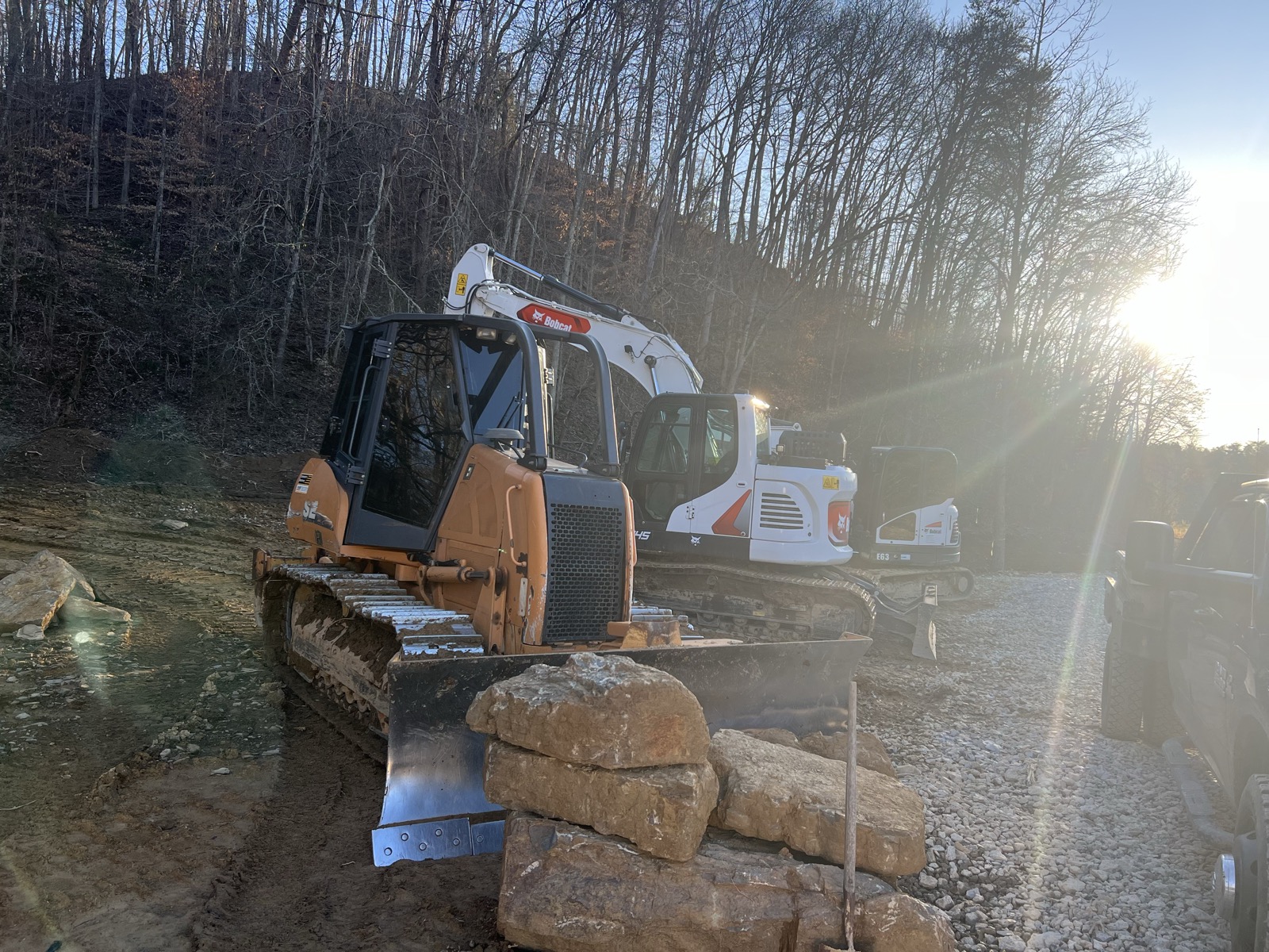 Bobcat dozer and excavator staged on a job site at sunset