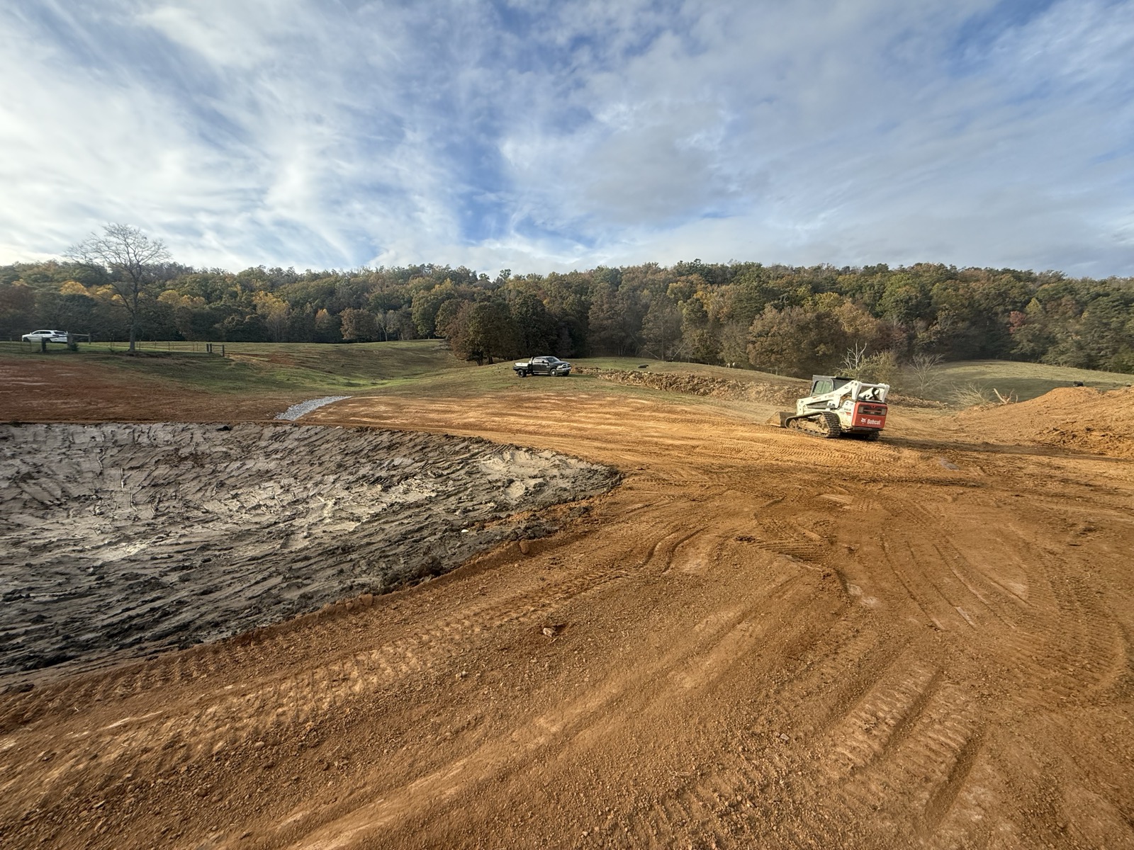 New pond construction with skid steer working the bank